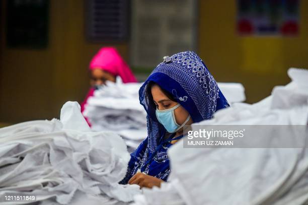 TOPSHOT - Labourers wearing facemasks work in a garment factory during a government-imposed lockdown as a preventive measure against the spread of the COVID-19 coronavirus in Dhaka on May 2, 2020. (Photo by MUNIR UZ ZAMAN / AFP) (Photo by MUNIR UZ ZAMAN/AFP via Getty Images)